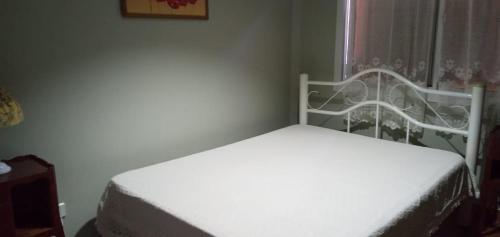 a white bed in a room with a window at La Casa de Irma in Valeria del Mar