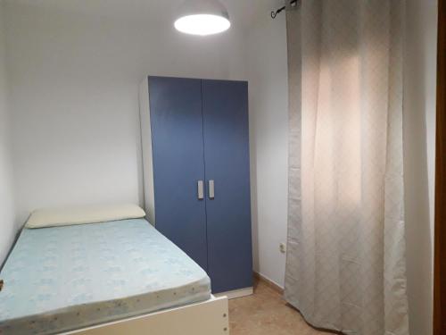 1 dormitorio con armario azul y cama en Apartamento Playa Cárabos, en Melilla