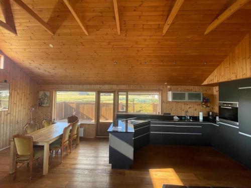 cocina con techo de madera, mesa y sillas en Glass House with Private River & 360° Views, en Stapi