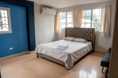 een slaapkamer met een bed met blauwe muren en ramen bij Blu Hostel in Panama-Stad