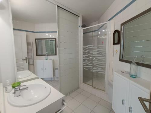 une salle de bain blanche avec un lavabo et une douche dans l'établissement Baie d'Azur, à Saint-Raphaël