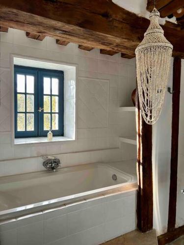 a white bathroom with a tub and a window at La Belle Vie du Vexin , à une heure de Paris in Parnes