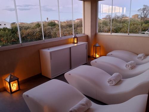 ラスカリにあるVille dell'Eden con 9 camere da letto in 6 unità abitativeの窓の前に白い椅子が4脚備わる客室です。