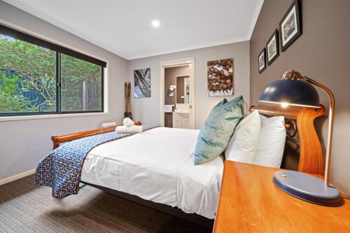 a bedroom with a large bed and a table at Acacia 2 Luxurious Holiday Townhouse in Jindabyne