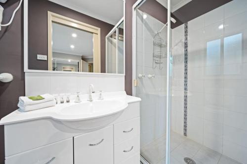 a white bathroom with a sink and a shower at Acacia 2 Luxurious Holiday Townhouse in Jindabyne