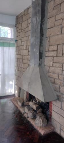 a stone fireplace with a metal hood over it at Pachamama in Uspallata