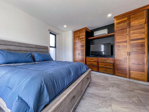 a bedroom with a bed with a television and wooden cabinets at Villa Bliss by Lumina in Cabo San Lucas