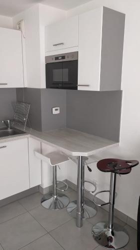 - une cuisine blanche avec une table et un four micro-ondes dans l'établissement Appartement Fodéré 2, à Nice