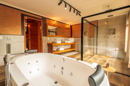a large bathroom with a tub and a glass shower at Pousada Cerejeiras in Monte Verde