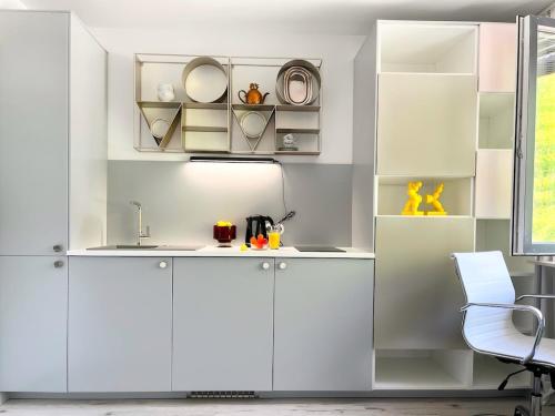 a white kitchen with white cabinets and a chair at COZY Studio at PARK near CITY-Center +NETFLIX +WIFI in Warsaw
