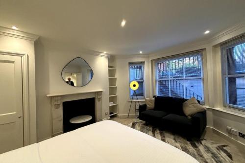 a living room with a black couch and a mirror at Chic Studio Flat 8 Mins to Harrods Knightsbridge in London