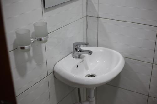 a white sink in a white tiled bathroom at Orchid Suites, Kira in Bulindo