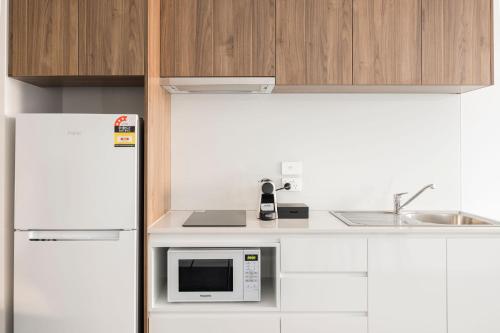 a kitchen with a white refrigerator and a microwave at Durham Serviced Apartments in Adelaide