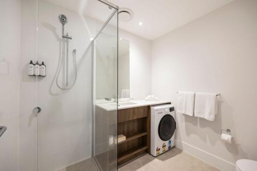 uma casa de banho com um chuveiro e uma máquina de lavar roupa em Durham Serviced Apartments em Adelaide