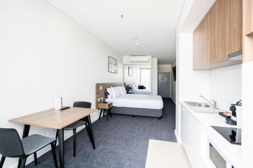 a hotel room with a bed and a table and chairs at Durham Serviced Apartments in Adelaide