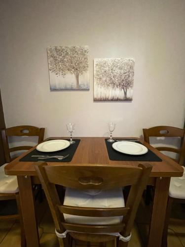 a wooden table with two plates and two paintings on the wall at Varousi House in Tríkala