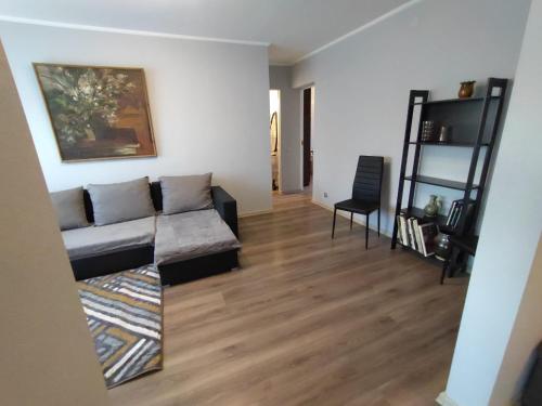 uma sala de estar com um sofá e um piso de madeira em Saknes apartamenti em Riga