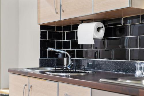 uma cozinha com um lavatório e um rolo de toalhas de papel em NEW Large luxurious 2 bed city penthouse + parking em Leicester