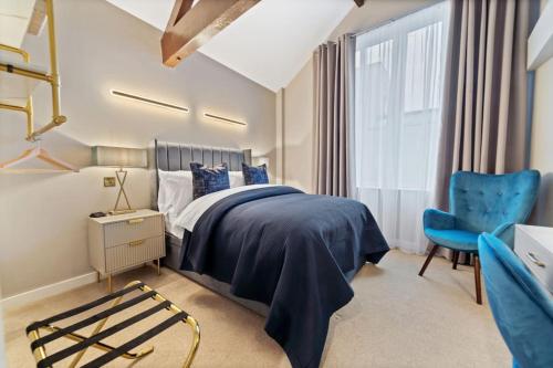 a bedroom with a bed and a blue chair at NEW Large luxurious 2 bed city penthouse + parking in Leicester