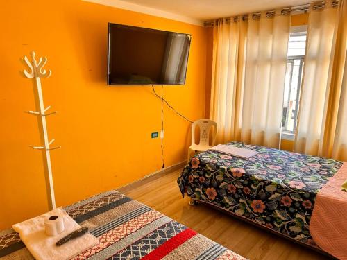 1 dormitorio con 1 cama y TV en la pared en la casa azul, en Huarmey