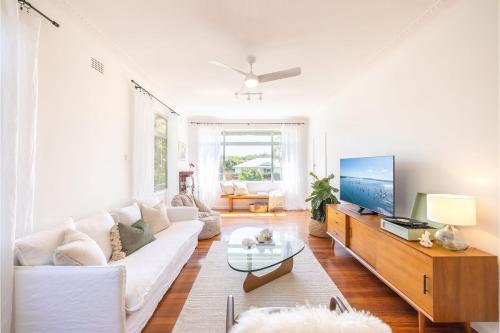 a living room with a white couch and a tv at Evoke - Shoal Bay, 2 Leonard Ave , Stylish holiday house with air con, Wi-Fi & boat parking in Shoal Bay