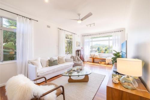 a living room with a white couch and a table at Evoke - Shoal Bay, 2 Leonard Ave , Stylish holiday house with air con, Wi-Fi & boat parking in Shoal Bay