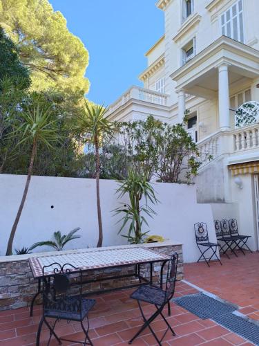 un patio avec une table et des chaises devant un bâtiment dans l'établissement Capt'ain Palladio appt 3 ch villa Belle époque Front de mer emplacement rare, à Saint-Raphaël
