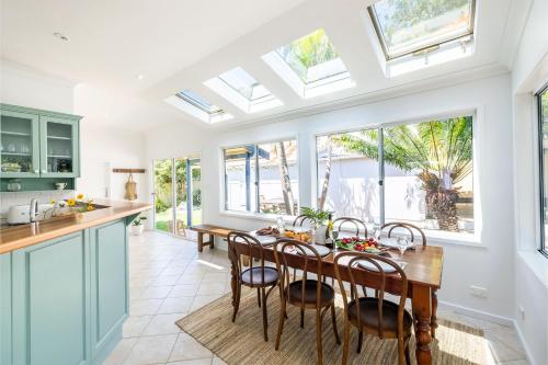 a kitchen with a table and chairs and windows at Evoke - Shoal Bay, 2 Leonard Ave , Stylish holiday house with air con, Wi-Fi & boat parking in Shoal Bay
