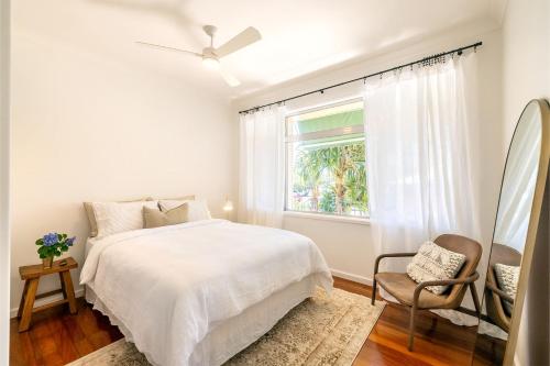 a white bedroom with a bed and a window at Evoke - Shoal Bay, 2 Leonard Ave , Stylish holiday house with air con, Wi-Fi & boat parking in Shoal Bay