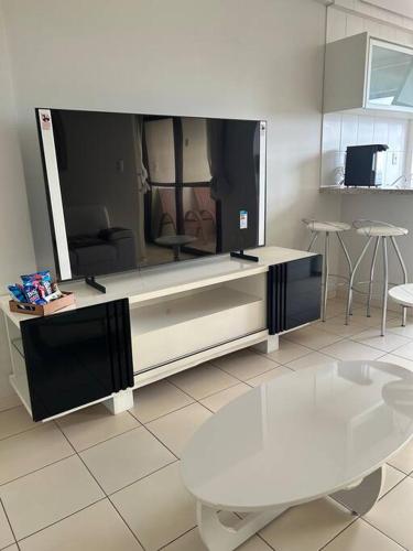 a living room with a large tv and a table at Flat completo no centro. in Palmas