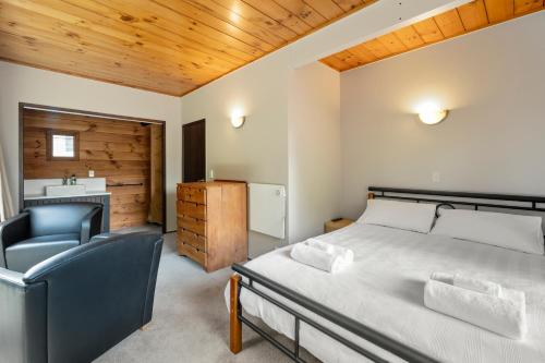 ein Schlafzimmer mit einem Bett, einem Stuhl und einem Waschbecken in der Unterkunft Kawaha on the Lake in Rotorua