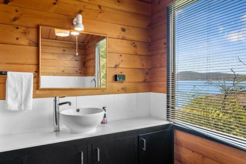 ein Bad mit einem Waschbecken und einem Spiegel in der Unterkunft Kawaha on the Lake in Rotorua