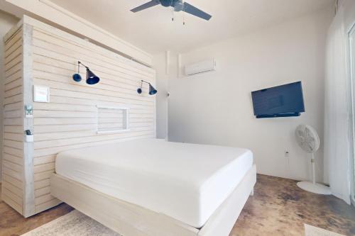 una camera bianca con letto bianco e TV a schermo piatto di White Sands Beach House a Maya Beach