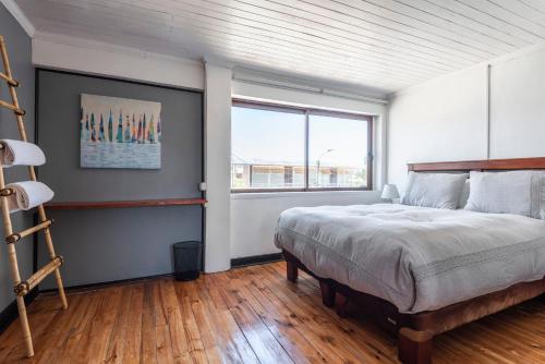 um quarto com uma cama grande e uma janela em LÖF Hostal em Pichilemu