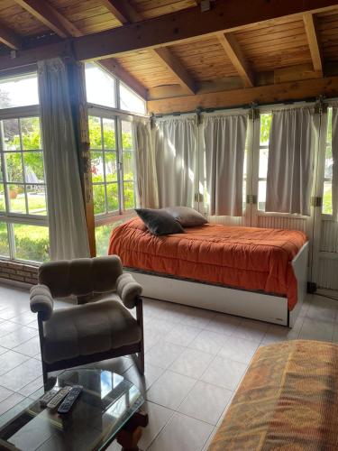 a bedroom with a bed and a chair and windows at Casa con pileta "TU CASITA EN VIEDMA" calle Junin 1877 in Viedma