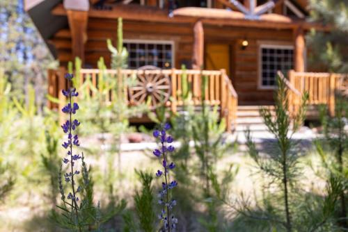 a log cabin with purple flowers in front of it at Fairlight Hollow in Bend