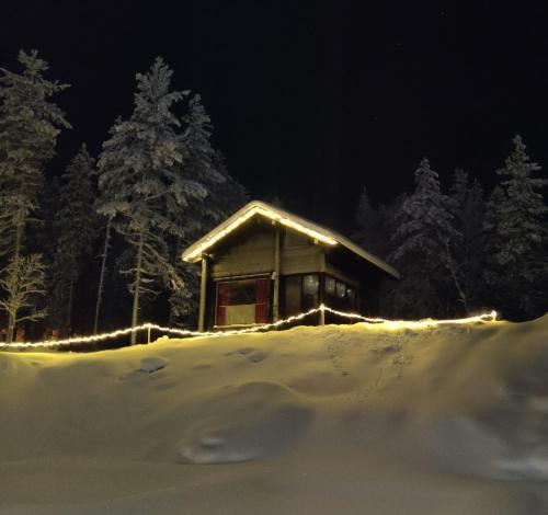 a cabin with lights in the snow at night at Lapland Aurora cabin in Rovaniemi