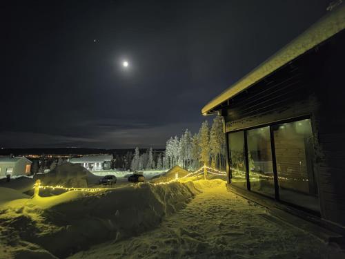 una vista nocturna de un patio cubierto de nieve con la luna en Lapland Aurora cabin, en Rovaniemi