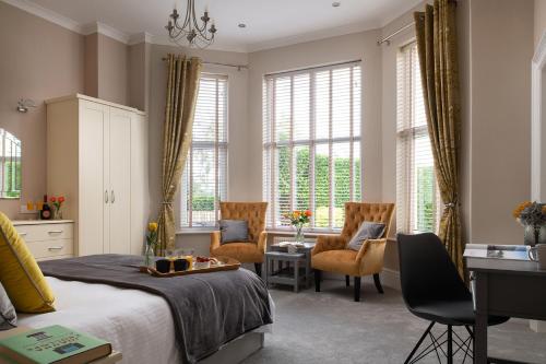 a bedroom with a bed and chairs and windows at Plas Meirion Apartment 3 in Trefriw