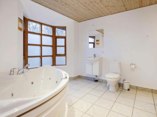 a white bathroom with a tub and a toilet at Holiday home Læsø in Læsø