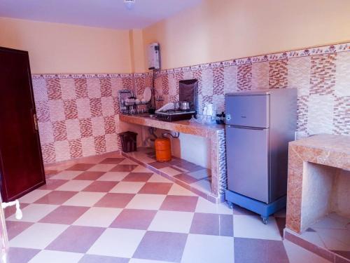 La cuisine est équipée d'un réfrigérateur et d'un sol en damier. dans l'établissement راحة المسافر، Rahat al moussafir, à Azilal