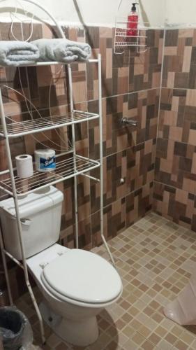 a bathroom with a toilet with a shelf above it at Hostal EL VALLE in Los Algarrobos