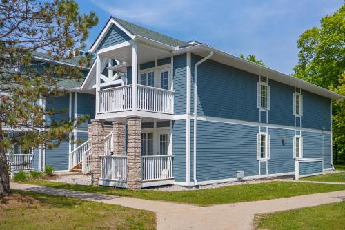 a blue house with a porch and balcony at Horseshoe Valley Suites - The Aurora in Shanty Bay