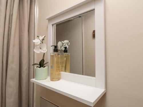 ein Badezimmer mit einem Spiegel und einer Vase mit Blumen in der Unterkunft Rose Lea in Saltburn-by-the-Sea