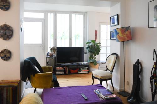 a living room with a tv and some chairs at Spacious duplex - near park in Paris