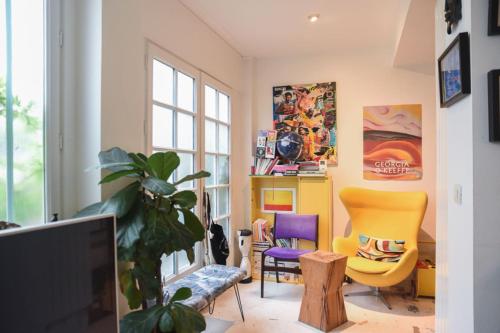 a living room with yellow and purple chairs and a tv at Spacious duplex - near park in Paris