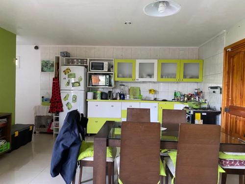 une cuisine avec des armoires vertes, une table et des chaises dans l'établissement Casa en Papudo, à Petorca