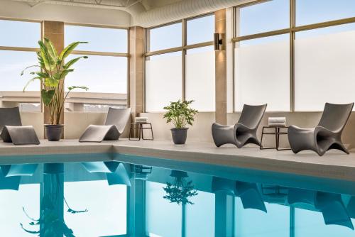 a swimming pool with chairs and plants in a building at Crowne Plaza Saint John Harbour View by IHG in Saint John