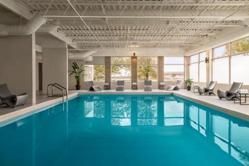 - une piscine d'eau bleue et des chaises dans un bâtiment dans l'établissement Crowne Plaza Saint John Harbour View, an IHG Hotel, à Saint-Jean