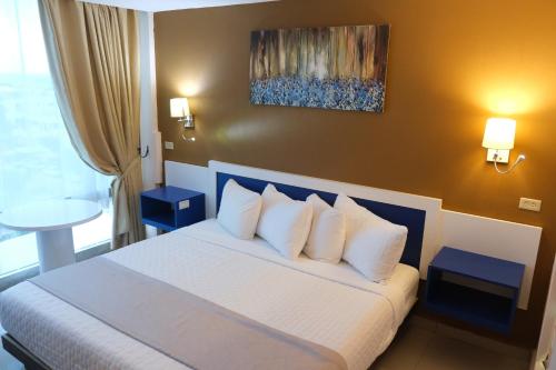 Habitación de hotel con cama con almohadas blancas en Golden Tree Hotel Belize en Ciudad de Belice